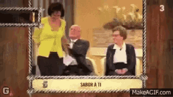a woman in a yellow jacket is standing next to a man in a tuxedo and two women sitting in chairs .