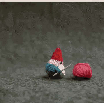 a stuffed animal with a red white and blue hat is playing with a ball of pink yarn