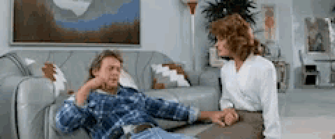 a man is laying on a couch while a woman sits next to him