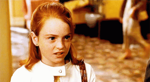 a young girl with red hair and freckles is making a funny face while standing in a hallway .
