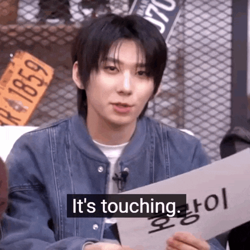 a young man holding a sign that says it 's touching .