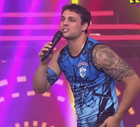 a man with a tattoo on his arm is singing into a microphone while wearing a blue tank top