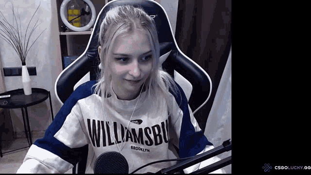 a girl wearing a williamsbu sweatshirt is sitting in a chair
