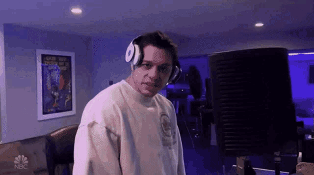 a man wearing headphones is standing in front of a computer monitor