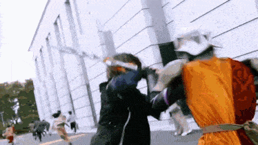 a group of people are standing in front of a building and fighting with swords .