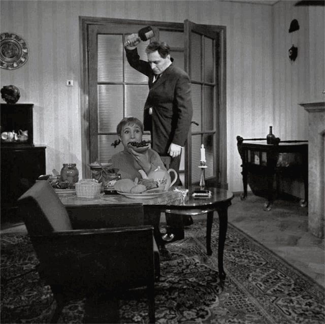 a man is holding a bottle over a woman 's head in a black and white photo