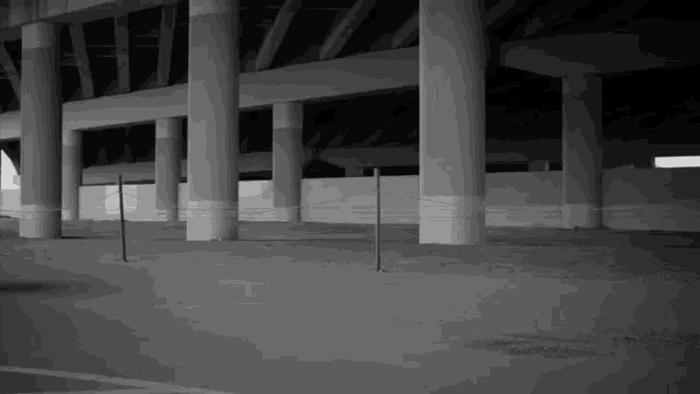 a black and white photo of an empty parking lot under a highway