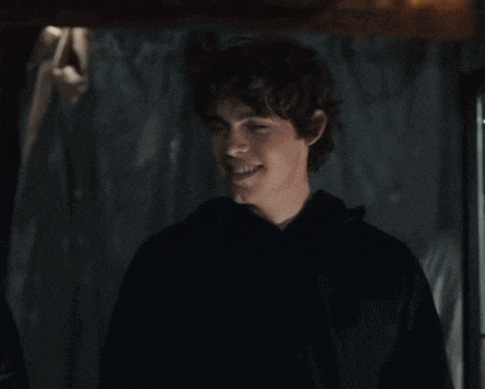 a man in a black hoodie is standing in a dark room .
