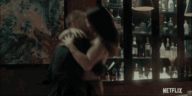 a woman is hugging another woman in front of a shelf full of bottles with netflix written on the bottom
