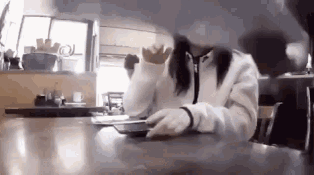 a woman is sitting at a table in a restaurant with a cell phone .