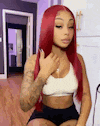 a woman with red hair is sitting on a chair in a kitchen wearing a white top and black shorts .
