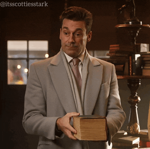 a man in a suit and tie holds a book in his hand