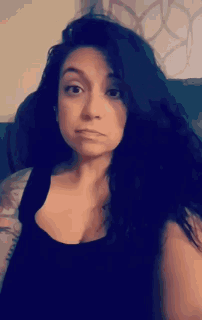 a woman with long black hair is making a face