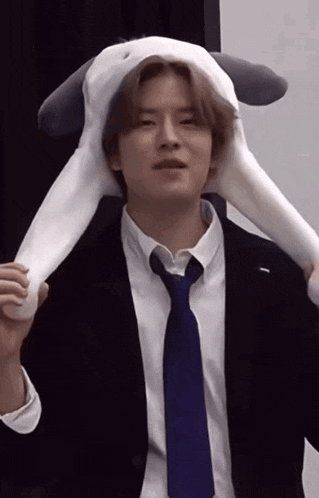 a man in a suit and tie is wearing a stuffed bunny hat on his head .