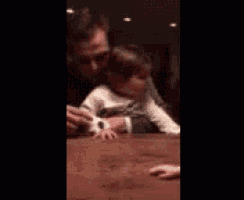 a man is holding a baby girl who is crawling on a table .