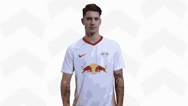 a man wearing a white shirt with a red bull on it giving an ok sign