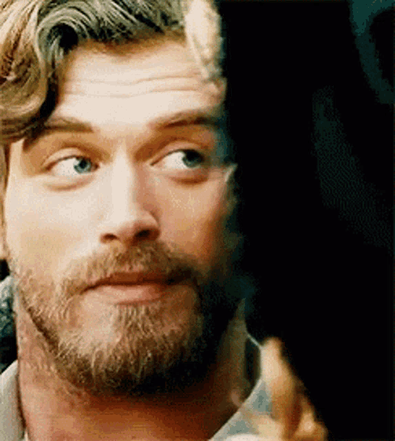 a close up of a man with a beard and blue eyes