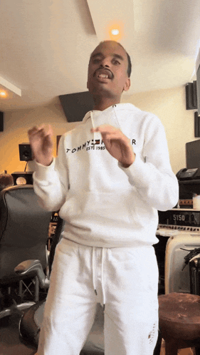 a man wearing a white tommy hilfiger hoodie and white sweatpants