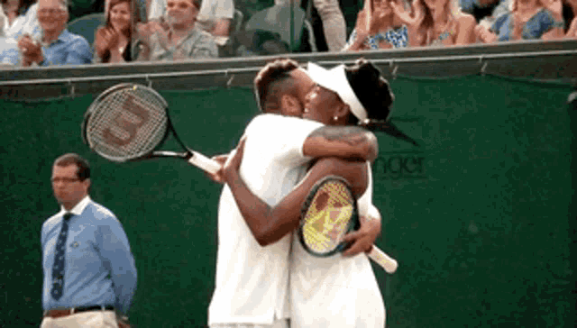 two tennis players hugging each other with a wilson racquet