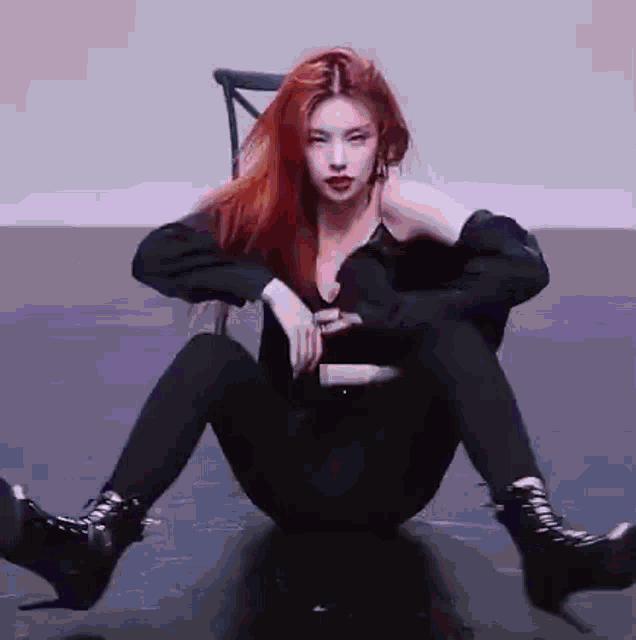 a woman with red hair is sitting on the floor wearing black leggings and boots .
