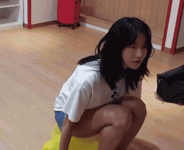 a woman is squatting down on a yellow object