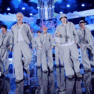a group of young men are dancing on a stage and one of them is wearing a bucket hat