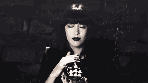 a woman in a black hat is holding a glass ball in her hand .
