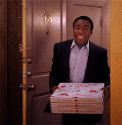 a man in a suit is carrying three pizza boxes in front of a door that says 303