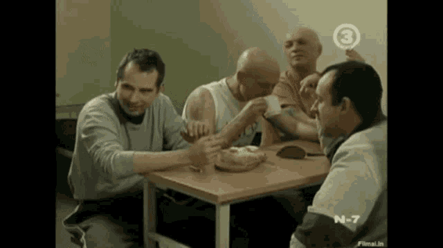 a group of men are sitting around a table with the number 3 on the top left
