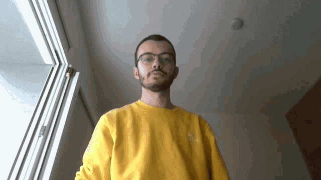 a man wearing glasses and a yellow shirt with a converse logo on the front