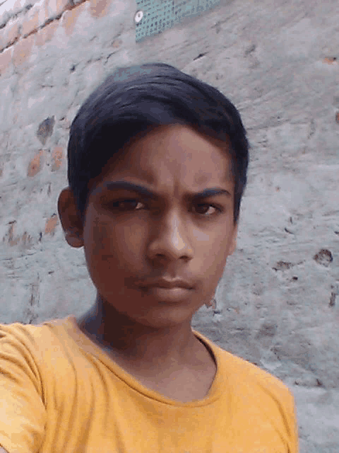a young boy wearing a yellow shirt is looking at the camera