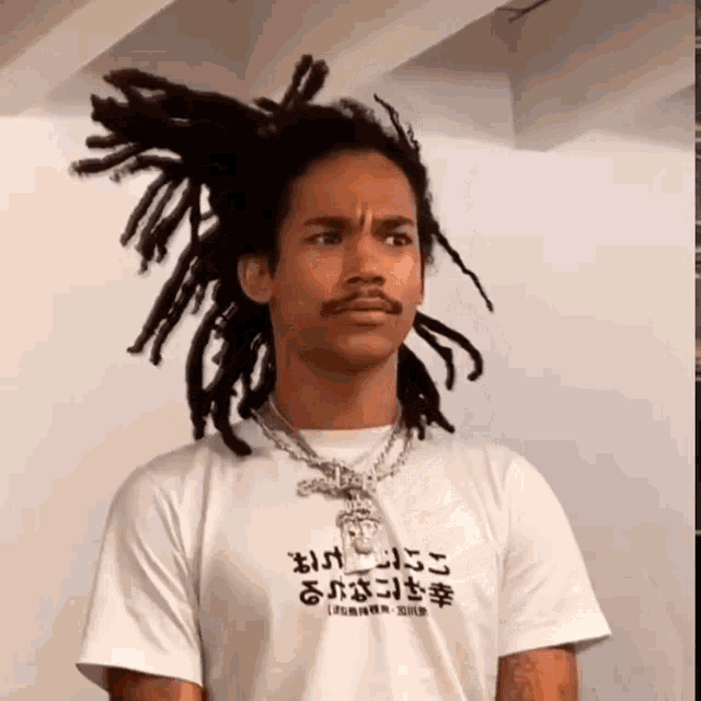 a man with dreadlocks is wearing a t-shirt that says ' jesus ' on it