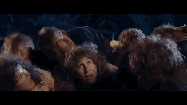 a group of people with curly hair are making funny faces in a crowd .