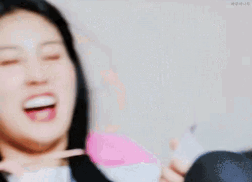 a woman is making a funny face while holding a pink toy .
