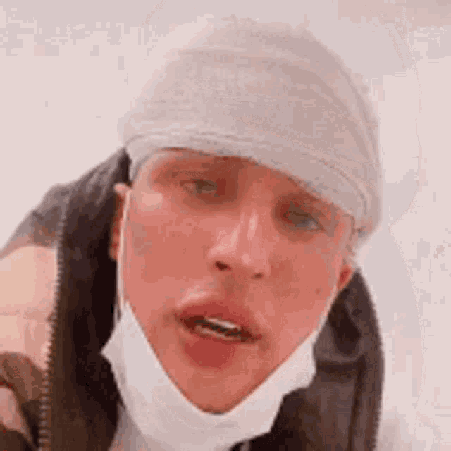 a man with a bandage on his head is wearing a mask .