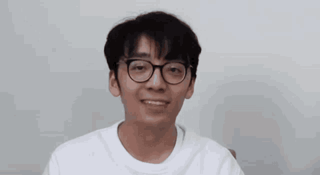 a young man wearing glasses and a white shirt is smiling with a heart above his head