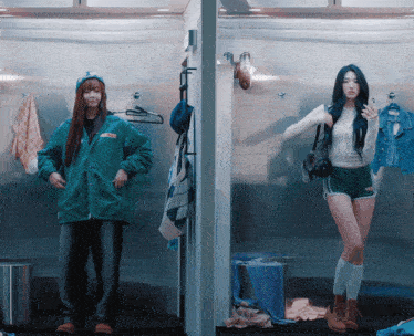 a woman in a green jacket stands next to another woman wearing shorts that say no