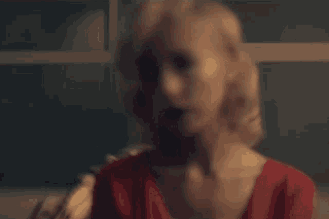 a woman with blonde hair and red eyes is wearing a red dress .