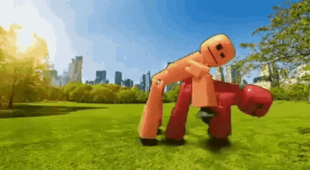 a couple of cartoon characters are standing on top of each other in a park with a city in the background .