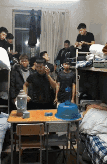 a group of people are gathered around a table in a dorm room