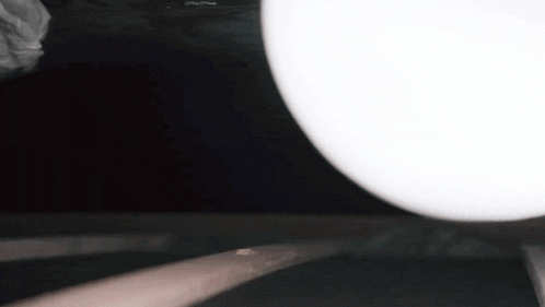 a close up of a person 's hand holding a white object in a dark room .