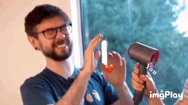a man wearing glasses is holding a hair dryer and giving a high five ..