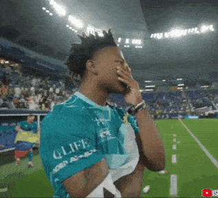 a soccer player wearing a shirt that says qlife is covering his face with his hand