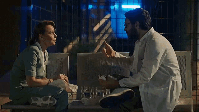 a man and a woman are sitting on a bench talking