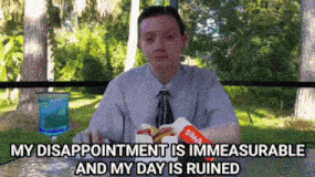 a man in a suit and tie is sitting at a table with a box of soda in his hand