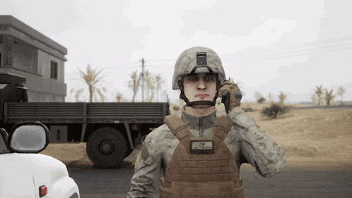 a soldier is talking on a walkie talkie with a truck in the background