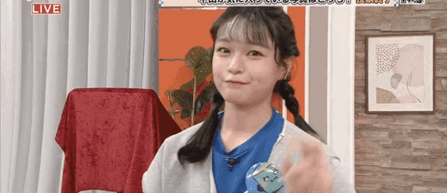 a girl in a blue shirt is standing in a room with a sign that says live on it