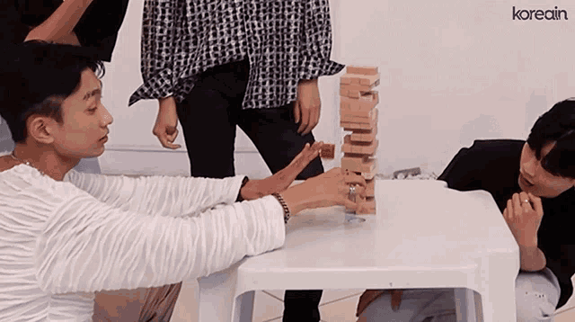 a group of people are playing a game called jenga with the word koreain on the bottom right