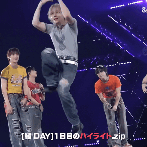 a man in a gray shirt is dancing on a stage with two other men