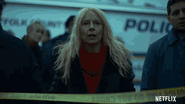 a woman in a red sweater stands in front of a police van